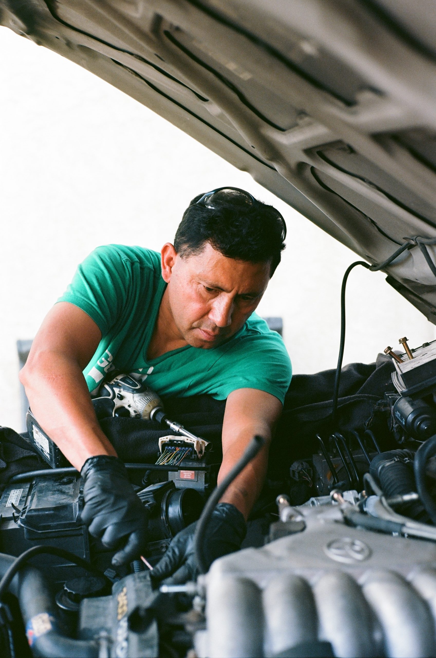 man in green shirt working on a car engine